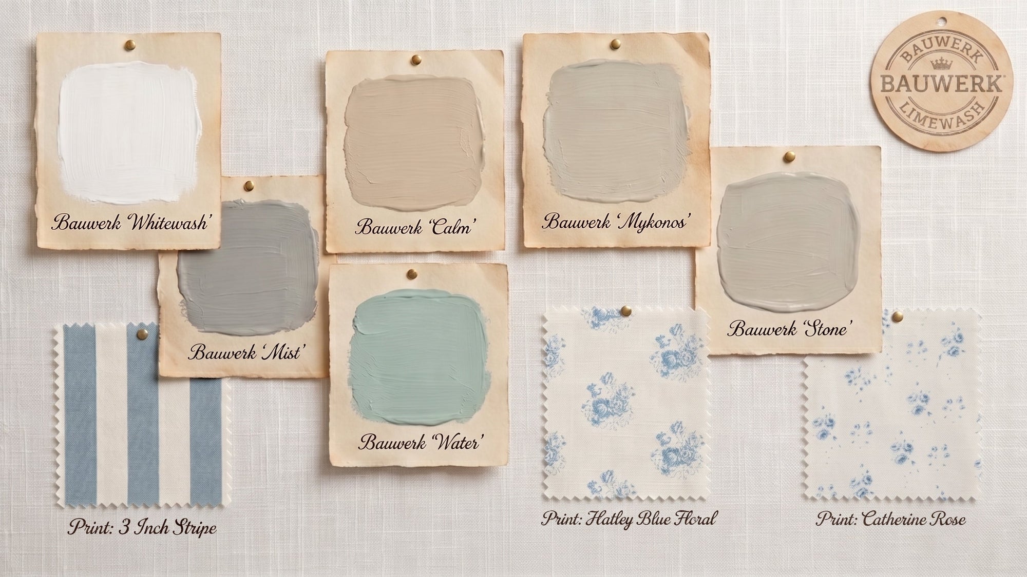 A set of eight paper swatch cards displaying different paint and wallpaper color options from Bauwerk and Bauwerk+Lathausch, arranged on a textured beige fabric background. The swatches include 'Bauwerk Whitewash', 'Bauwerk Calm', 'Bauwerk Mykonos', 'Bauwerk Mat', 'Bauwerk Water', 'Bauwerk Stone', 'Print: 3 Ink Stripe', 'Print: Holly Blue Flower', and 'Print: Catherine Rose'.