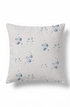 A square throw pillow in a light beige linen fabric with a blue shibori tie-dye floral pattern, shown against a plain white background.