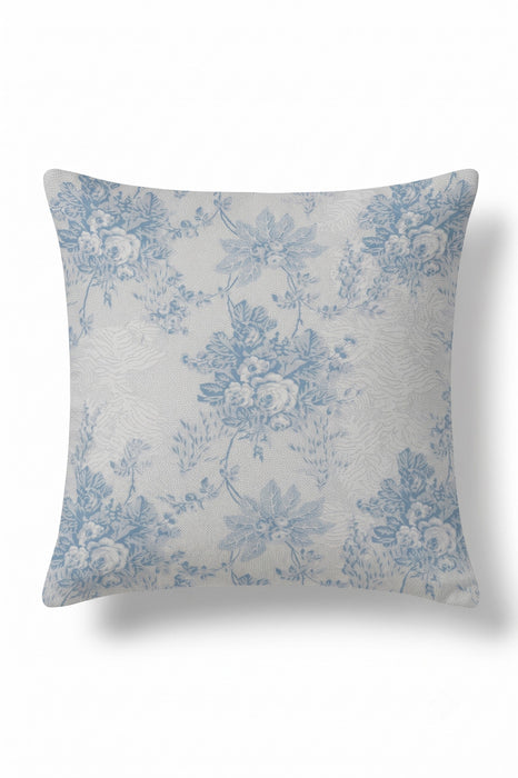 A square throw pillow featuring a classic blue floral toile de Jouy pattern on a textured off-white background, shown against a plain white studio backdrop.